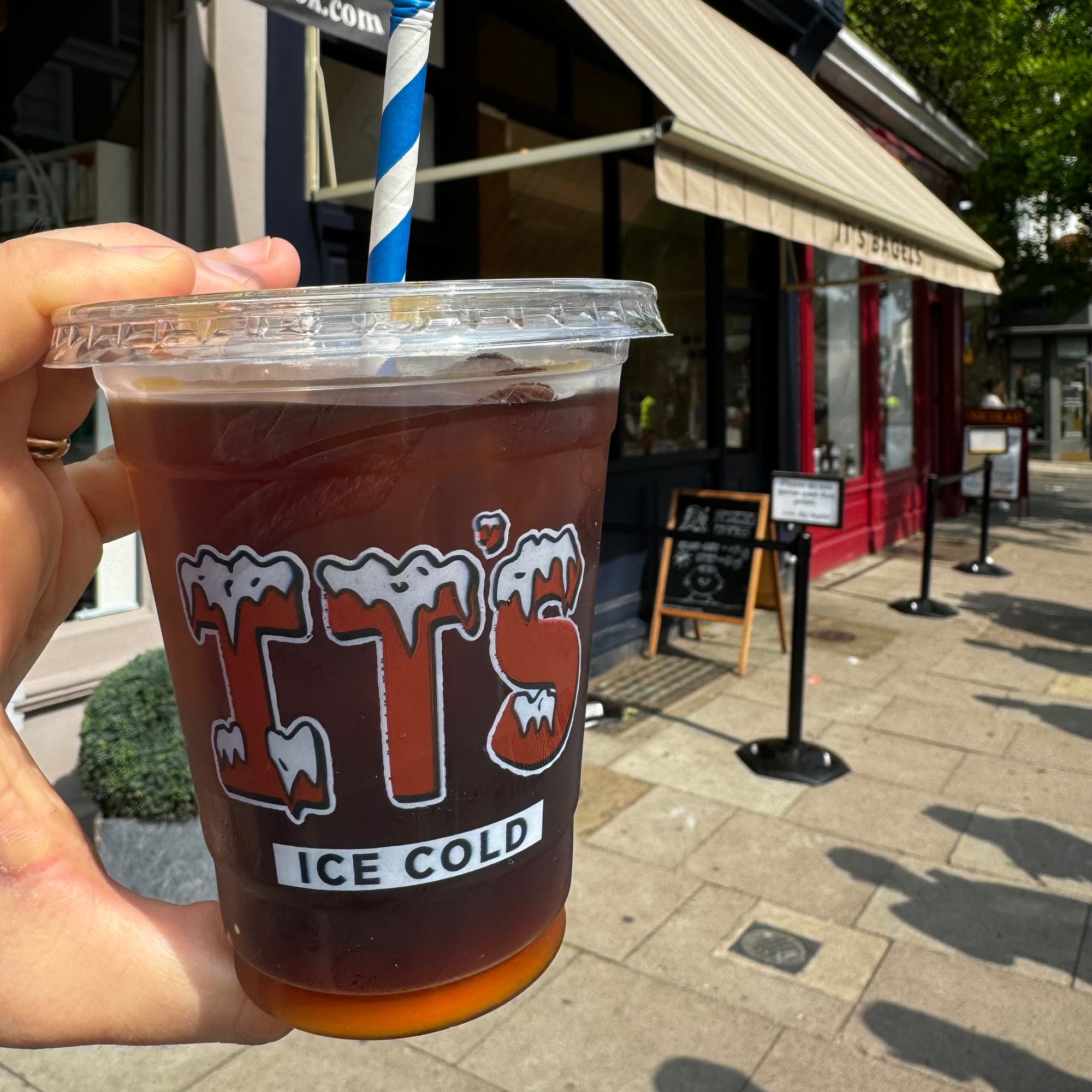 A plastic cup filled with iced coffee. Branding on the side reads "It's Ice Cold"