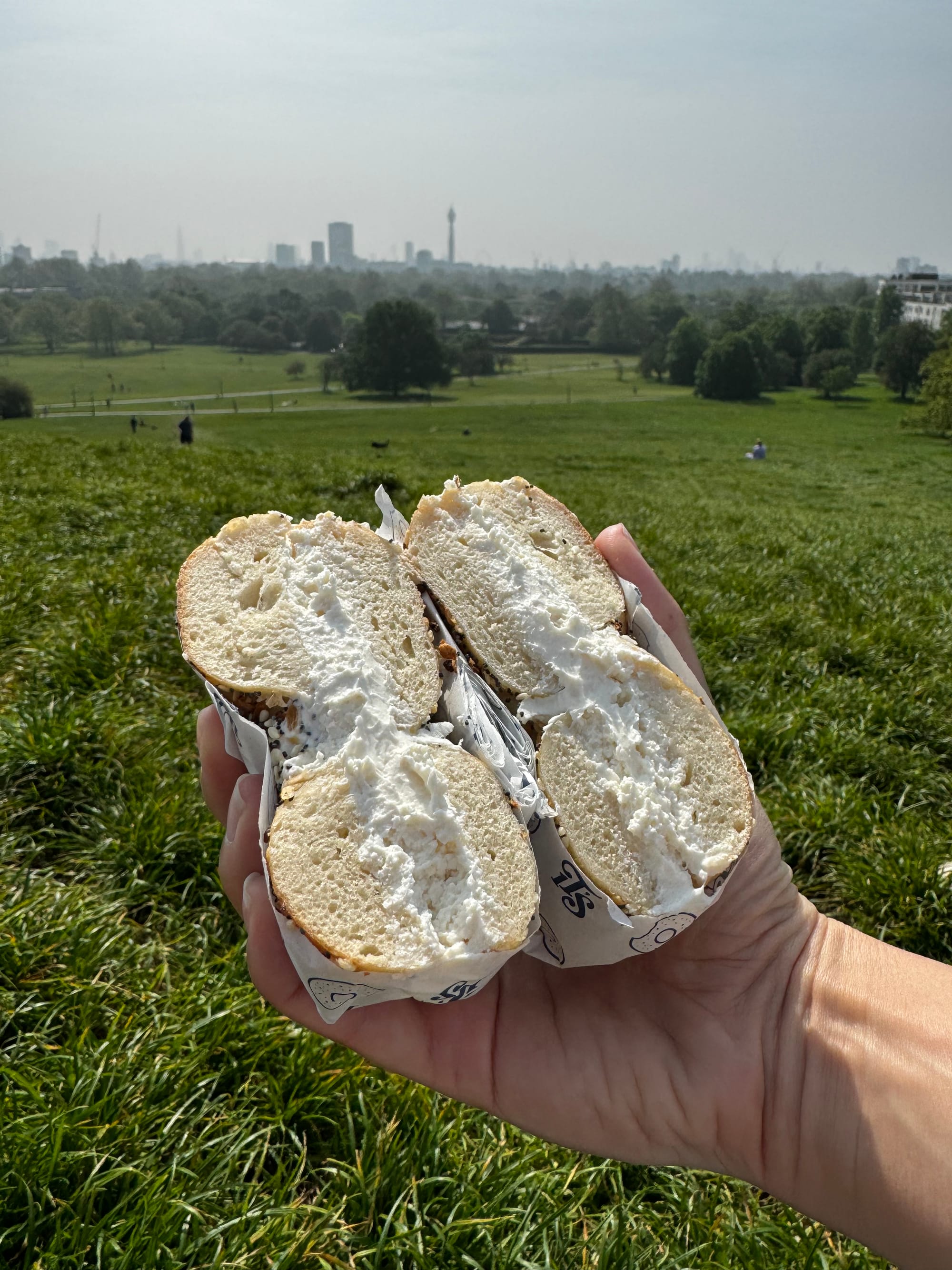 The It's Bagel bagel with plain vegan cream cheese on Primrose Hill, skyline in background.
