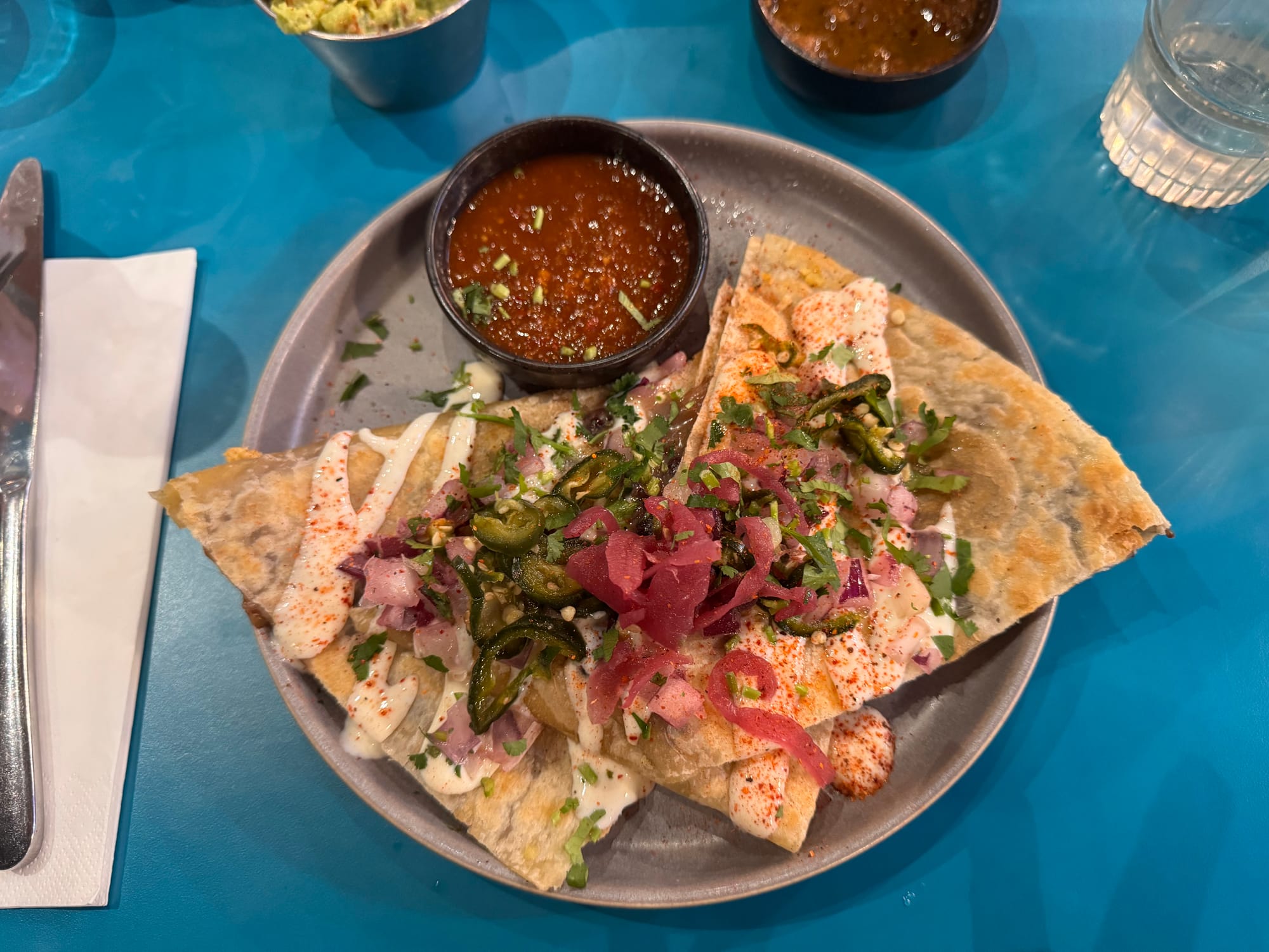 An aerial shot of the quesadilla, which looks nice, with a lot of colorful toppings.