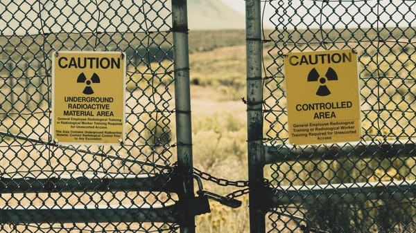 A chain link gate with two "Caution: Radioactive Material" signs attached.